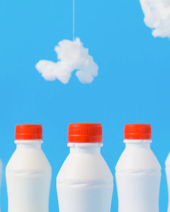 A line of milk bottles with a sky backgroung.