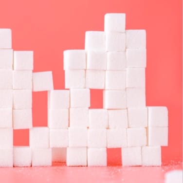 Multiple stack sugar cubes in a pink background.