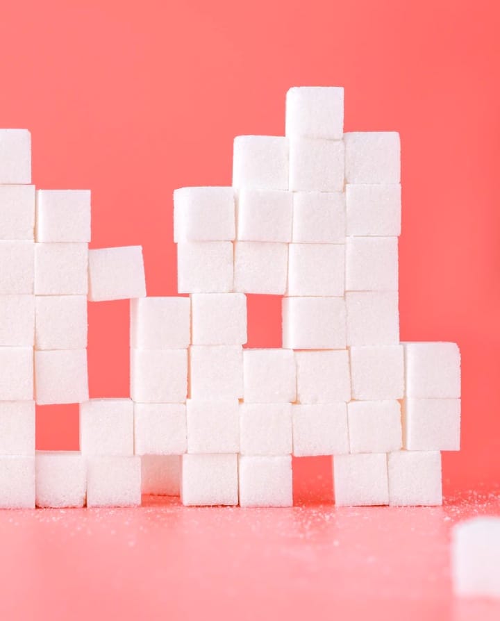 Multiple stack sugar cubes in a pink background.