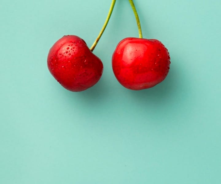 A cherry on a green background.