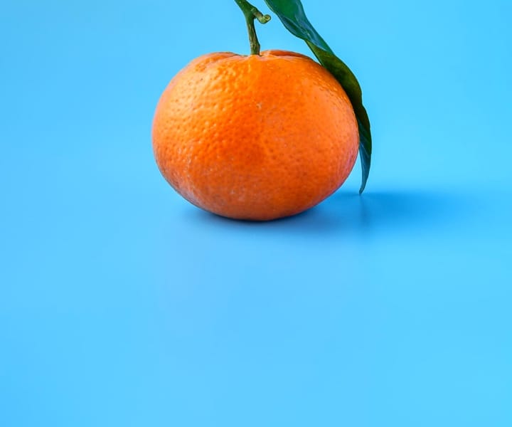 A clementine on a blue background.