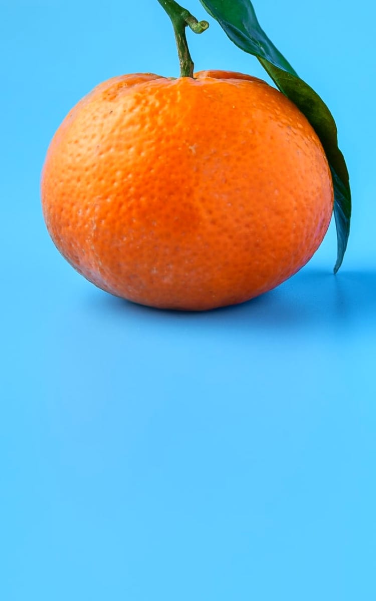 A clementine on a blue background.